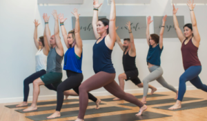 yoga class full of people doing warrior one pose